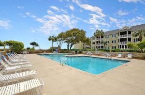 a swimming pool with lounge chairs and a building at PC202E: 202E Port O'Call in Isle of Palms