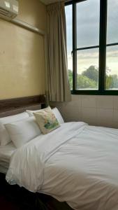 a bedroom with a white bed with two windows at 虎尾五八五民宿 in Huwei