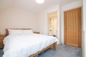 a bedroom with a white bed and a wooden door at Vine Mews - 2 Bed in Warwick
