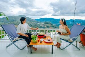 a man and woman sitting at a table on a balcony at ม่อนล้านวิว ม่อนแจ่ม in Ban Pong Khai Tai +4 photos