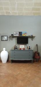 una stanza con una cassettiera con una televisione e una chitarra di Palazzo Saraceno apartments-Antico Rifugio a Taranto