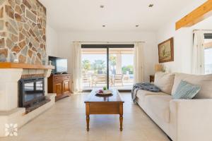 ein Wohnzimmer mit einer weißen Couch und einem Kamin in der Unterkunft Villa Sapphire by Abahana Villas in Teulada
