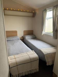 deux lits dans une petite pièce avec une fenêtre dans l'établissement Seaside Charm Cabin Retreat in Rhyl, à Rhyl