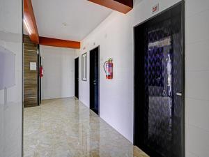 a hallway with white walls and a painting on the wall at Hotel O Gangeshwar in Anand