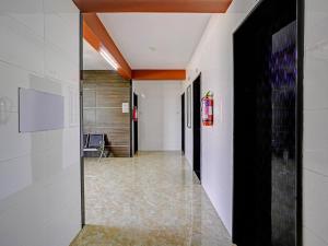 a hallway with white walls and a black door at Hotel O Gangeshwar in Anand