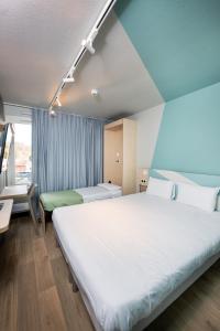 a hotel room with a large white bed in a room at Ibis Budget Lyon Caluire Cité Internationale in Caluire-et-Cuire