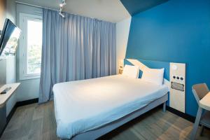a bedroom with a white bed and a blue wall at Ibis Budget Lyon Caluire Cité Internationale in Caluire-et-Cuire +53 photos