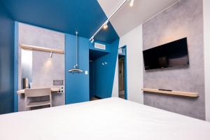 a bedroom with a bed and a tv on a wall at Ibis Budget Lyon Caluire Cité Internationale in Caluire-et-Cuire
