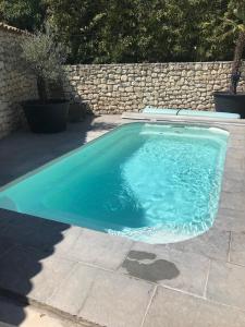 une petite piscine bleue avec un mur en pierre dans l'établissement Villa des Rosiers, à La Celle-sous-Gouzon