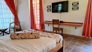a bedroom with a bed and a flat screen tv at Od Kidi Cottages in Migori