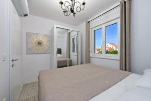 een witte slaapkamer met een bed en een raam bij Apartment Amarilis in Mandre