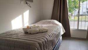 una cama con dos animales de peluche con una ventana en Loft San Lorenzo, en Bahía Blanca
