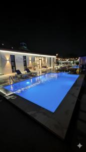 a large swimming pool at night with blue lights at Farmhouse-Villa--فيلا-المزرعة in Hatta