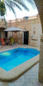 a large blue swimming pool next to a building at Villa Dar El Bey in Tozeur