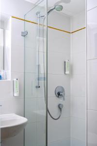 a shower with a glass door next to a sink at Hotel Obertor in Ravensburg +101 photos