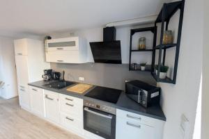 a kitchen with white cabinets and a microwave at Modern Apartment Bedburg-Hau in Bedburg Hau +8 photos