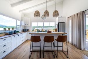 a kitchen with white cabinets and a large island with chairs at The White House - Kleinkrantz in Wilderness