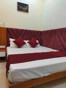 a bedroom with a large bed with red pillows at Hotel Shree Shyam Palace in Ujjain