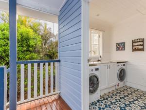 a laundry room with a washer and dryer on a balcony at Cedar House character retreat in Bangalow in Bangalow