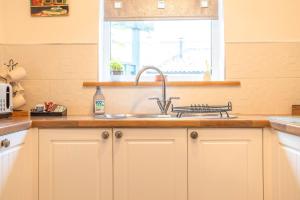 une cuisine avec un évier et une fenêtre dans l'établissement Taylor Cottage, à St Andrews 45 autres photos