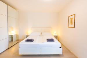 a white bedroom with a white bed and two lamps at 204 Paris 59m2 4-8 Pers extr Bedroom in Klagenfurt