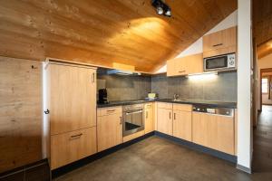 a kitchen with wooden cabinets and a wooden ceiling at Landal Brandnertal in Bürserberg +16 photos
