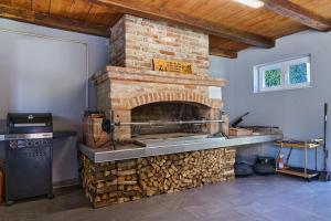 a kitchen with a brick oven with a pile of wood at Oaza Mira LAZE in Nova Gradiška