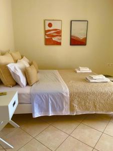 a bedroom with a bed with two pictures on the wall at Mesogaia Home Near ATH Airport in Markopoulo