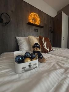 Un osito de peluche sentado en una cama con una caja de pelotas. en Hotel Cavalli - Winterwonderland, en Blankenberge