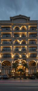 un edificio illuminato con macchine parcheggiate di fronte di Helmond Hotel a Erbil