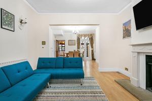 ein Wohnzimmer mit einer blauen Couch und einem Kamin in der Unterkunft Spacious charming house near Heathrow in Feltham