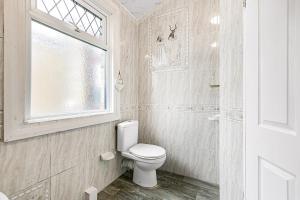 ein Badezimmer mit Toilette und Fenster in der Unterkunft Spacious charming house near Heathrow in Feltham + 13 Fotos