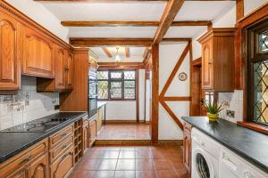 eine große Küche mit Holzschränken und einem Fenster in der Unterkunft Spacious charming house near Heathrow in Feltham
