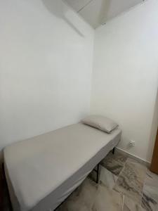a bed in a room with a white wall at Mus Lim Homestay Aqil Bandar Puncak Alam in Bandar Puncak Alam +1 photo