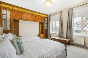 ein Schlafzimmer mit zwei Betten und einem Tisch und Fenstern in der Unterkunft Spacious charming house near Heathrow in Feltham