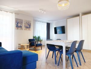 a living room with a white table and blue chairs at Kolory Warmii Apartament Niebieski in Olsztyn