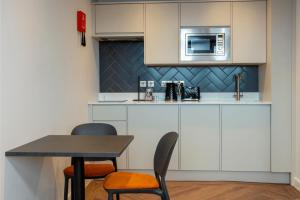 a kitchen with a table and chairs and a microwave at Station Suites Aparthotel in Middlesbrough