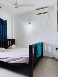 Ce lit se trouve dans un dortoir doté d'un mur blanc. dans l'établissement Green apartment, à Ambulgama