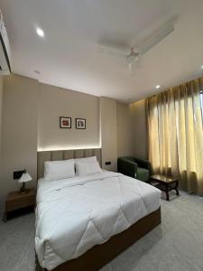 a bedroom with a large white bed and a chair at Modern Hotel Restaurant and Bar in Mathura