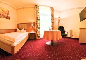 a hotel room with a bed and a table at Hotel-Pension Vier Jahreszeiten in Bad Elster