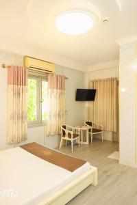 a bedroom with a bed and a table and a television at Khách Sạn An Chi in Ho Chi Minh City