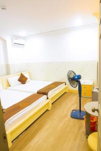 a room with two beds and a fan in it at Khách Sạn An Chi in Ho Chi Minh City