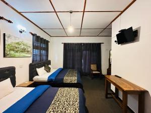 a hotel room with two beds and a television at New Royal Mount Hotel in Nuwara Eliya