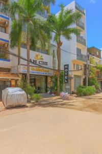 a building with palm trees in front of a street at Khách Sạn An Chi in Ho Chi Minh City +26 photos