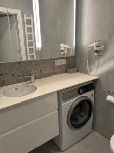 a bathroom with a washing machine and a sink at Apartament Homar AKTENA Shellter Rogowo in Rogowo