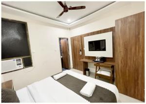 RāmnagarにあるHOTEL - SRK DIVINE Palace - Near The Holy Shree Kashi Vishwanath Temple - Free Wi-Fi & Fully Air Conditioning Hotel - Restrurant & Lift Facility - Best Hotel In Varanasiのベッドとテレビがあるホテルの部屋 +10枚の写真