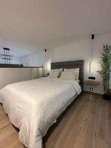 een slaapkamer met een groot wit bed en een potplant bij PrimeLoft 1 in Tríkala