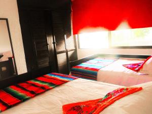 een slaapkamer met 2 bedden en een rode muur bij Casa Pok Tapok in Cancun