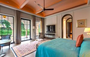 a bedroom with a bed and a table and some windows at The Oberoi Rajgarh Palace in Rājgarh