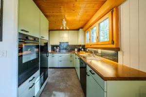a kitchen with white cabinets and a wooden ceiling at Mountain Apartment - Hot Tub & Sunset Views in Axalp